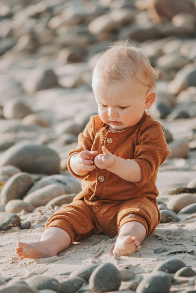 baby wearing orange onesie beach photoshoot